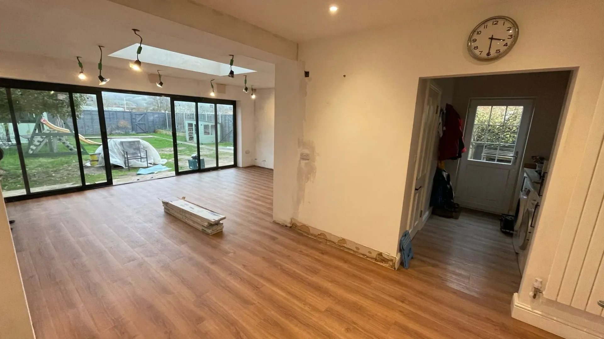 A house extension under renovation with new wooden-style flooring and large bi-fold glass doors.