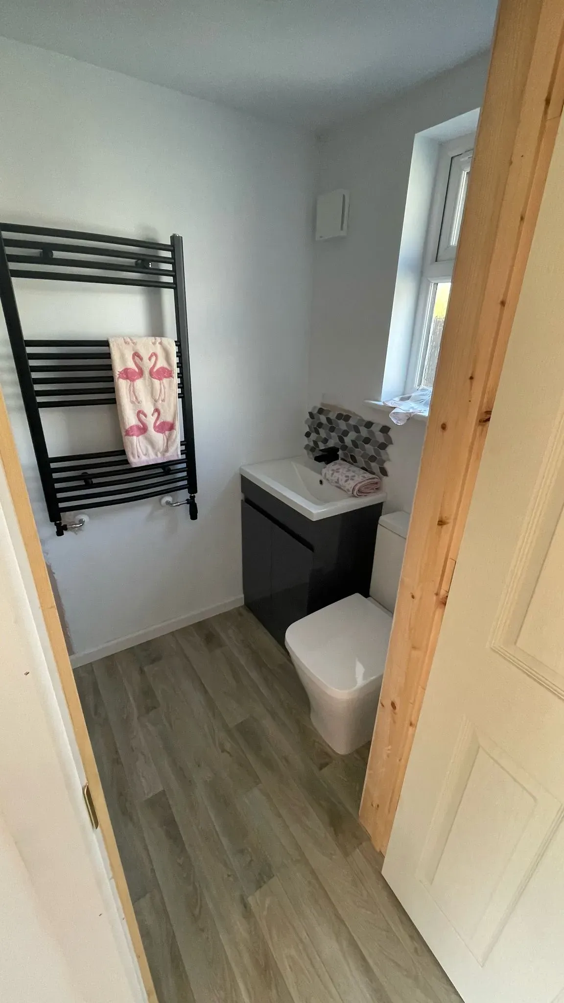 Modern small bathroom renovation featuring a black towel rail and grey vanity unit.