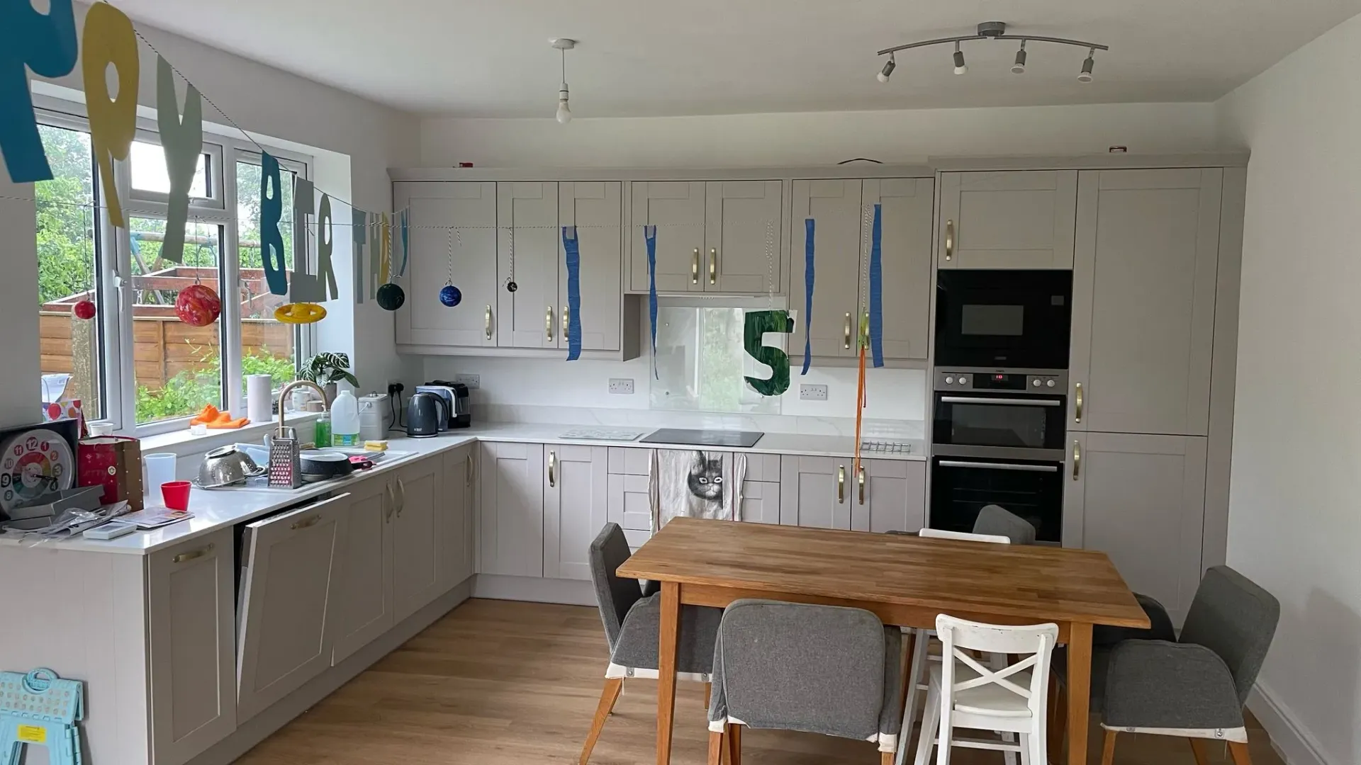 Modern light grey shaker-style kitchen installation with dining table by DP Carpentry & Building LTD in Hatherley, Gloucestershire