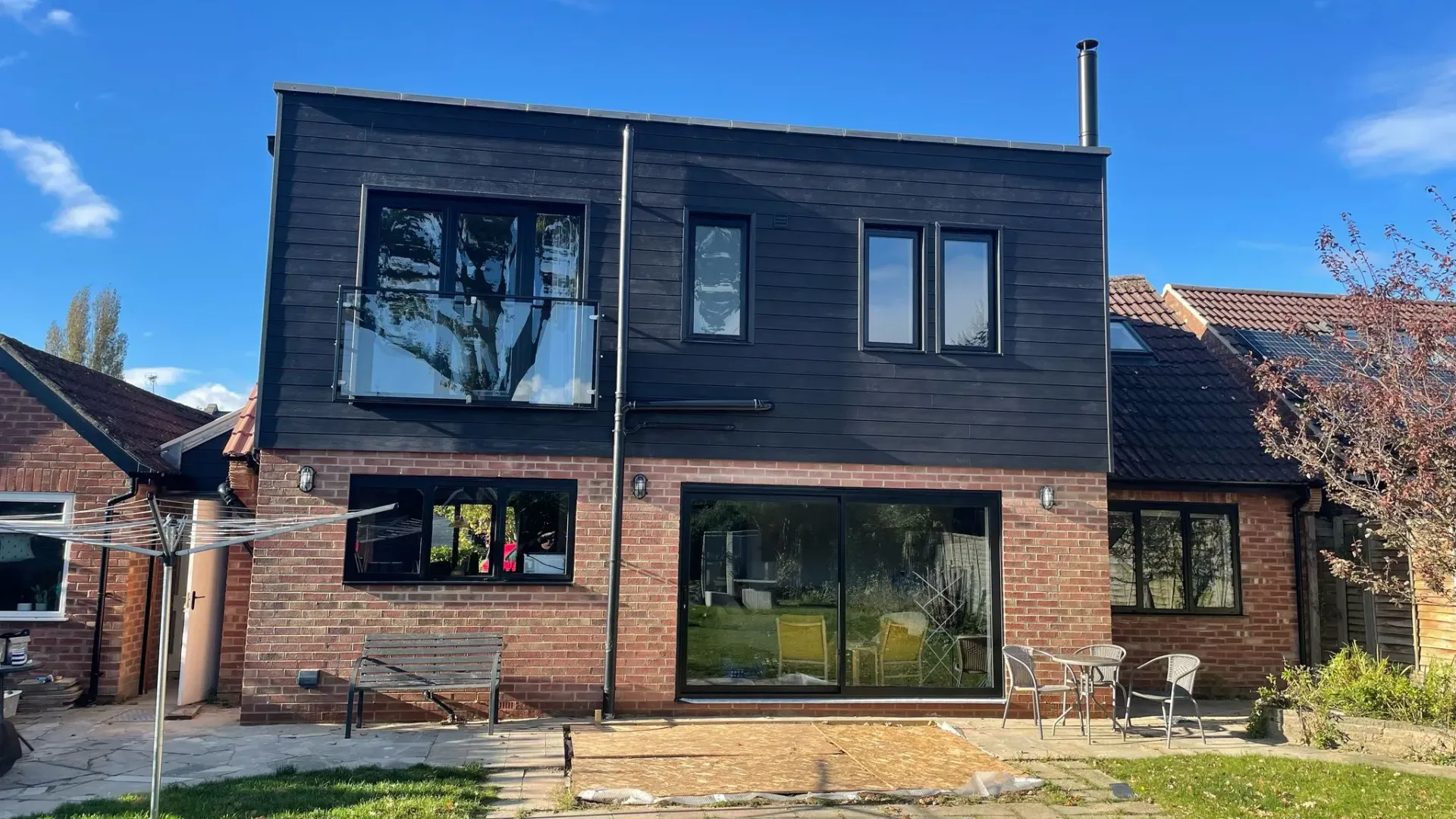 Modern two-storey home extension in Gloucestershire by DP Carpentry & Building LTD, showing dark cladding and brick finish.