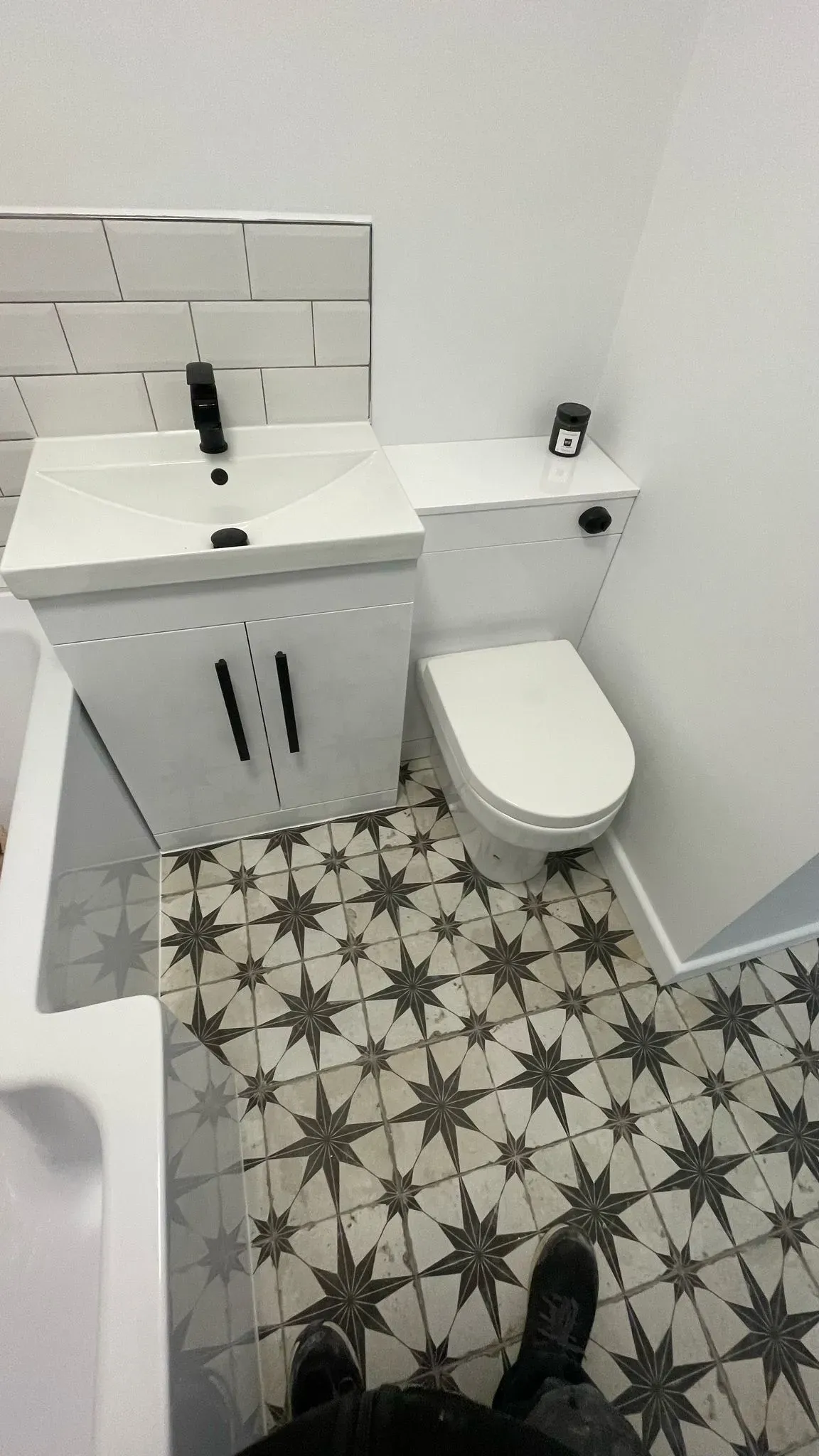 A modern bathroom renovation in Cheltenham featuring patterned floor tiles and a white vanity unit by DP Carpentry and Building LTD.