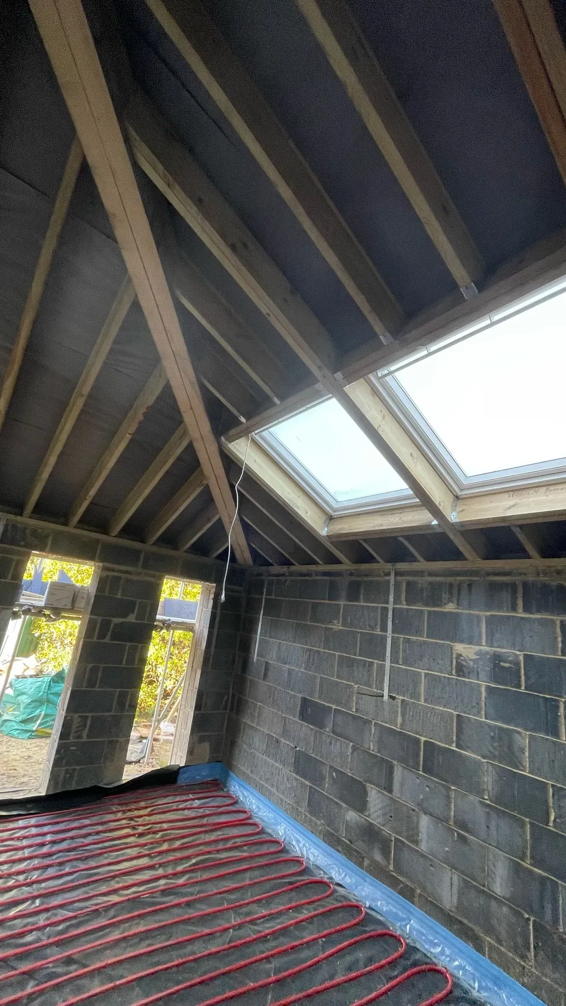 Internal view of a home extension construction site with roof windows and underfloor heating