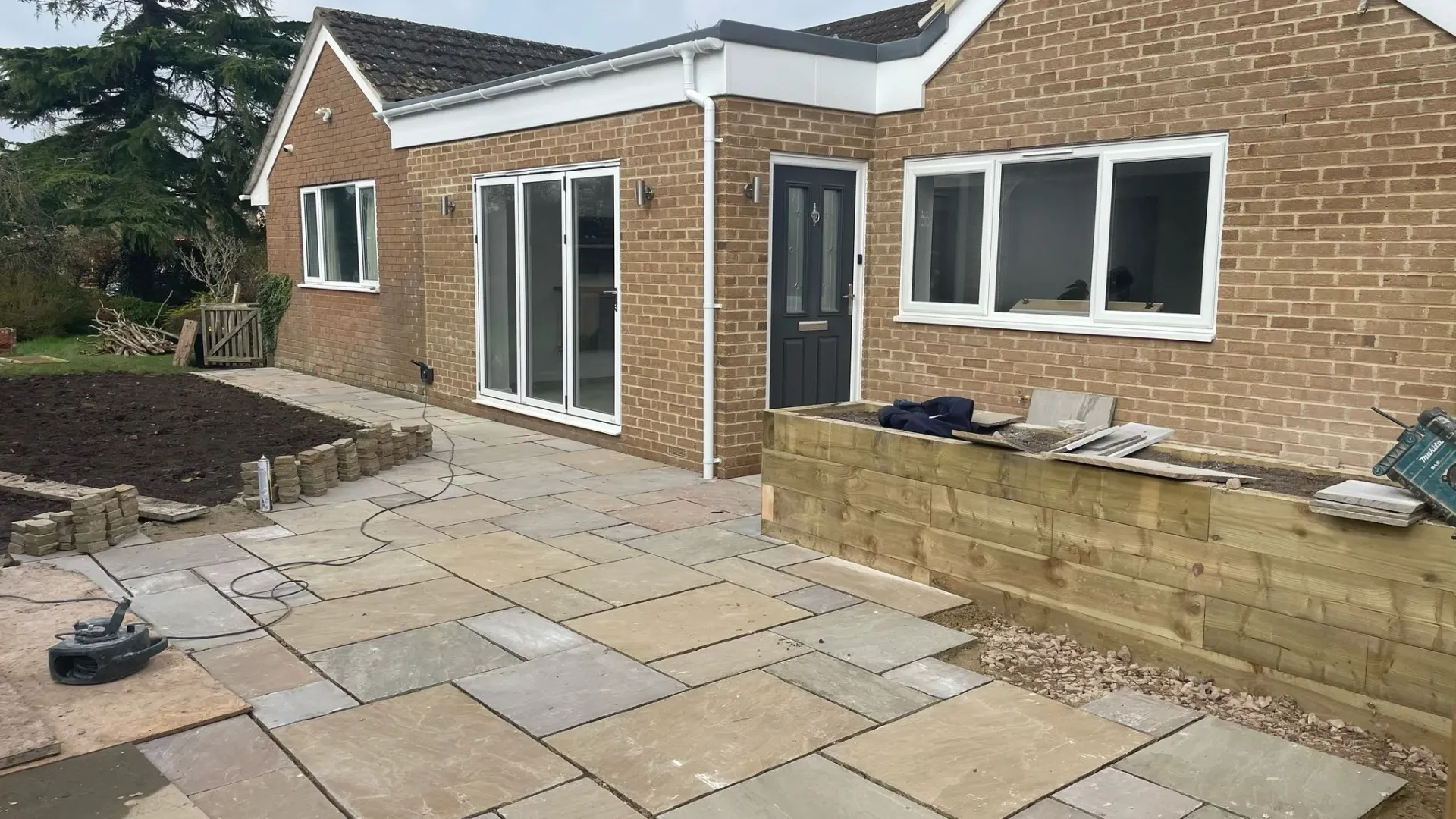 Exterior view of a house renovation in Hatherley showing a new patio installation and groundwork by DP Carpentry & Building LTD.